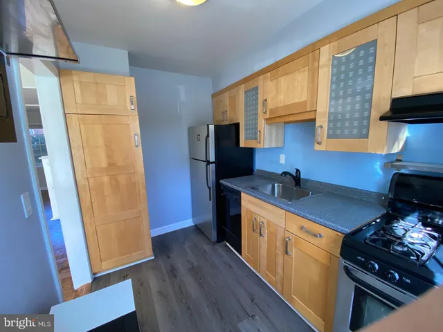 a kitchen with stainless steel appliances granite countertop a refrigerator a sink dishwasher a stove and a dining table with wooden floor