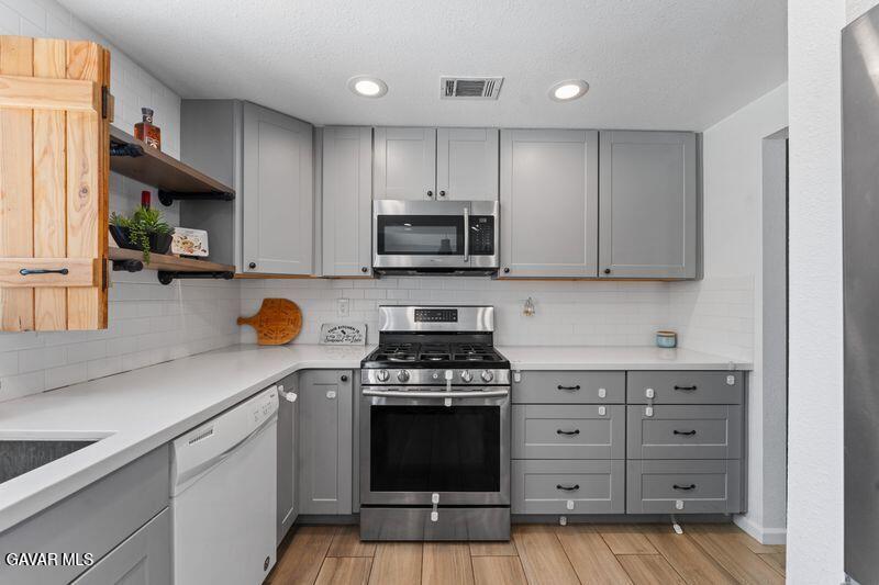 44246 Ruthron Avenue Lancaster, CA 93536 - Photo 12 of 31 a kitchen with granite countertop a stove and a wooden cabinets