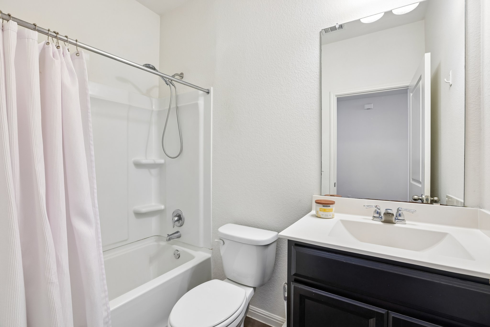 19105 Mike Mansfield Road Manor, TX 78653 - Photo 21 of 28 Functional full bathroom featuring a tub-shower combination, a vanity with a sleek countertop, and a wide mirror