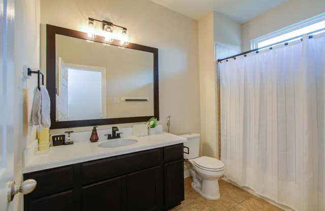 a bathroom with a double vanity sink toilet and mirror