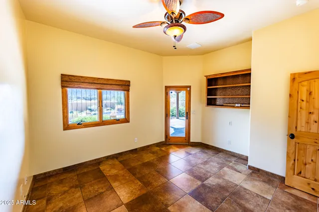 an empty room with chandelier fan and windows