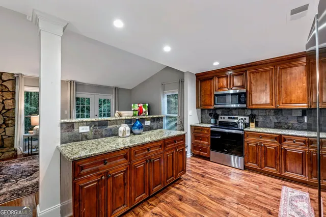 a kitchen with stainless steel appliances granite countertop wooden cabinets a sink dishwasher a stove and a refrigerator