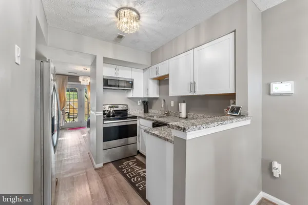 a kitchen with stainless steel appliances granite countertop a stove top oven a sink and a refrigerator