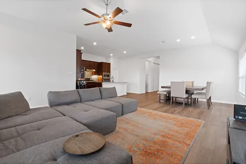 a living room with furniture and a dining table with wooden floor
