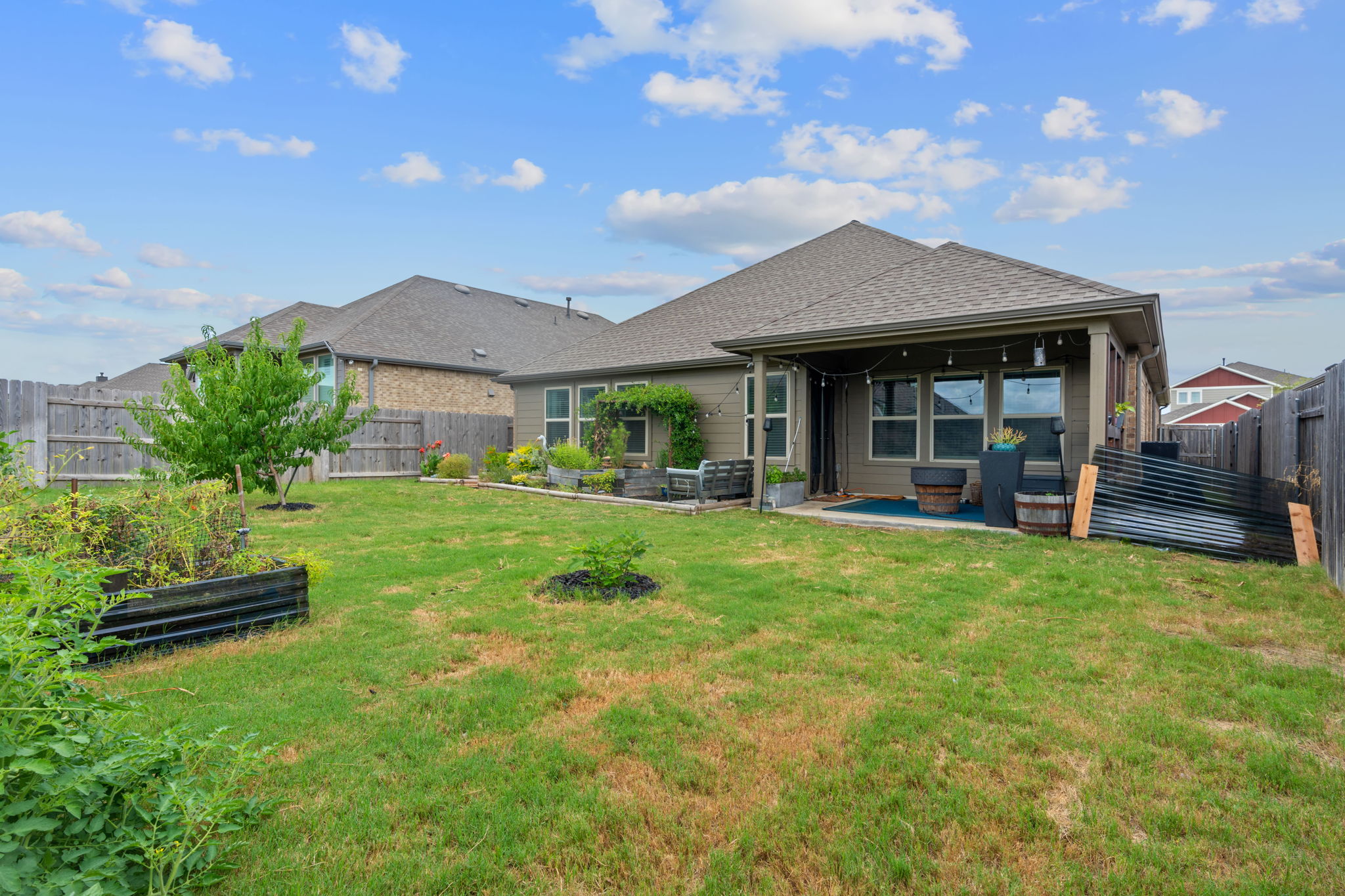 213 Treasure Trove Path Kyle, TX 78640 - Photo 28 of 29 Rear view of property featuring a fenced backyard, a patio area, a garden, and roof with shingles