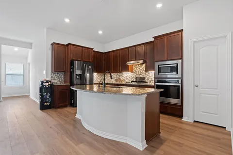 a kitchen with stainless steel appliances kitchen island granite countertop a refrigerator and a stove top oven