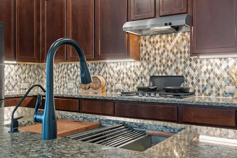 a kitchen with stainless steel appliances granite countertop a sink and a stove