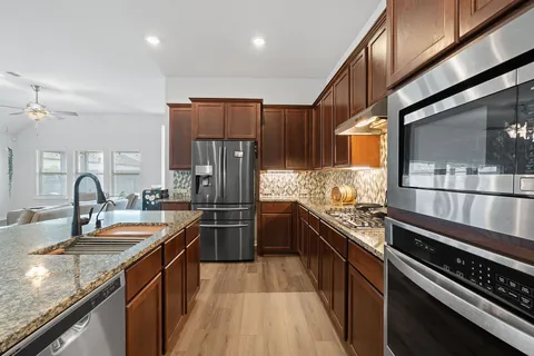 a kitchen with stainless steel appliances granite countertop a sink a stove and a refrigerator