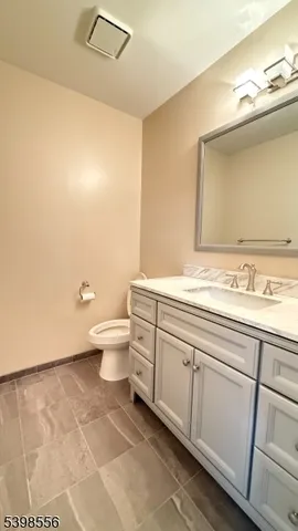 a bathroom with a granite countertop sink a toilet and a mirror