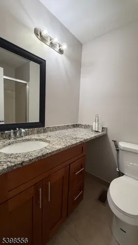a bathroom with a granite countertop sink and a toilet