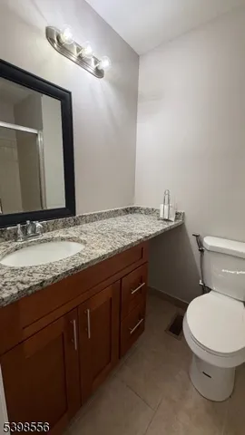 a bathroom with a granite countertop toilet sink and mirror