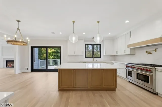 a large kitchen with kitchen island a stove a sink a center island and wooden floor