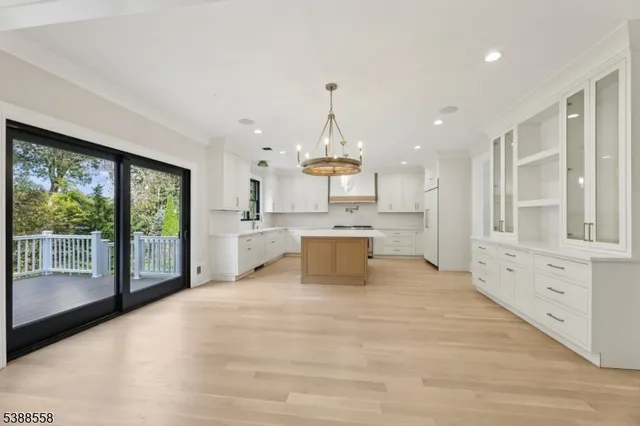 a large white kitchen with granite countertop a large counter top stainless steel appliances and cabinets