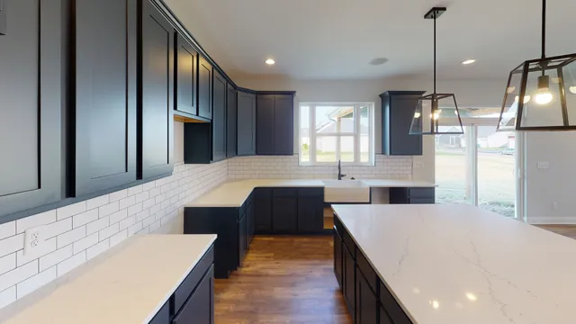 a large kitchen with kitchen island a stove a sink a refrigerator white cabinets and wooden floor