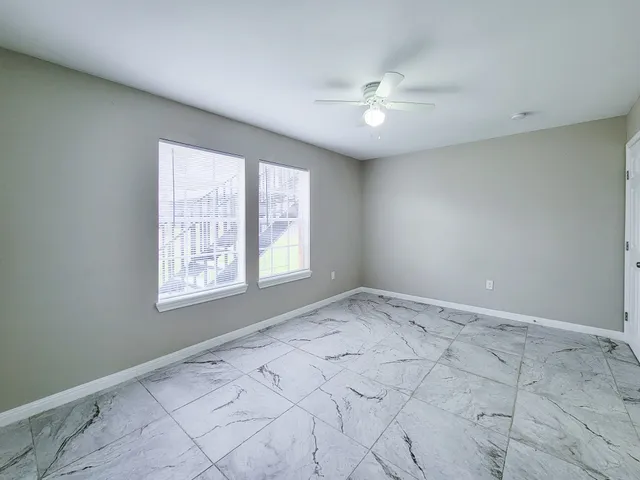 en empty room with windows and chandelier fan