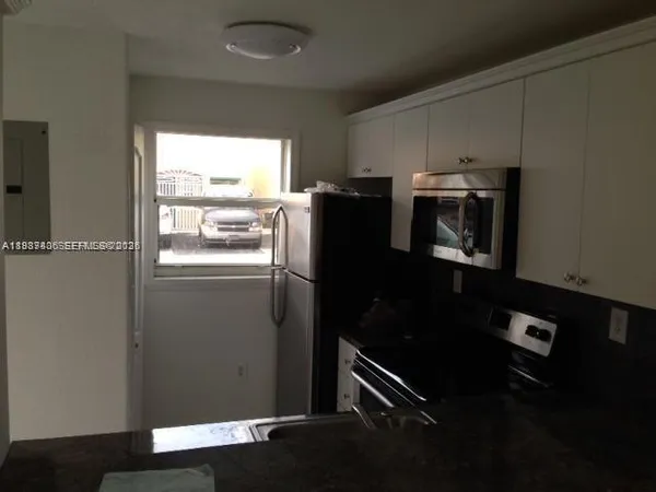 a kitchen with metallic refrigerator and window