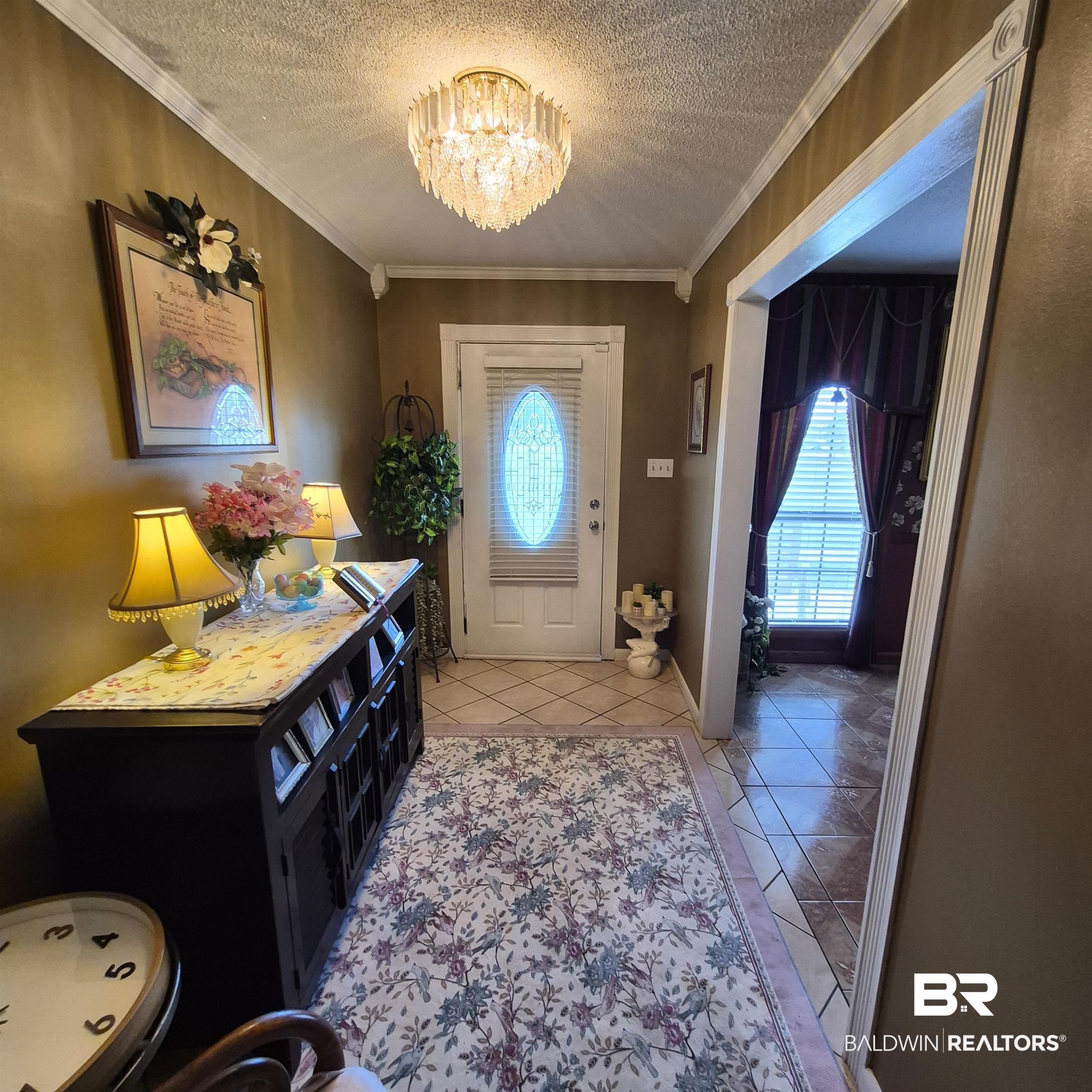 26635 Highway 41 Range, AL 36473 - Photo 21 of 74 Foyer entrance featuring light tile patterned floors, hanging lights, a textured ceiling, ornamental molding, and healthy amount of natural light
