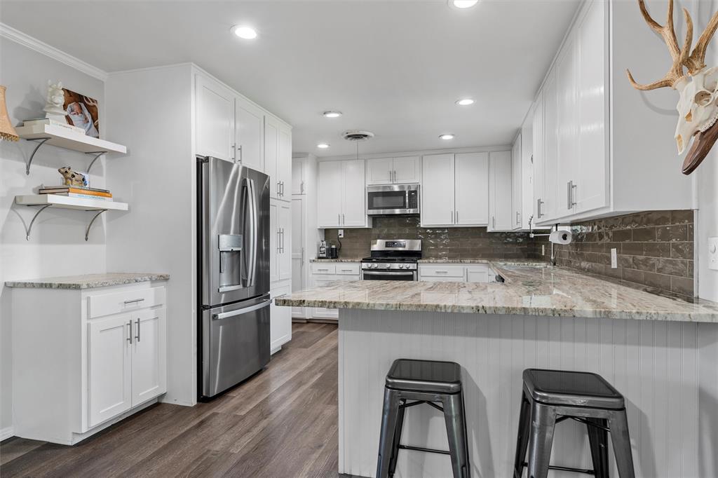 6224 Summit Ridge Drive Waco, TX 76710 - Photo 8 of 25 a kitchen with stainless steel appliances granite countertop a refrigerator a sink dishwasher a stove and white countertops with wooden floor