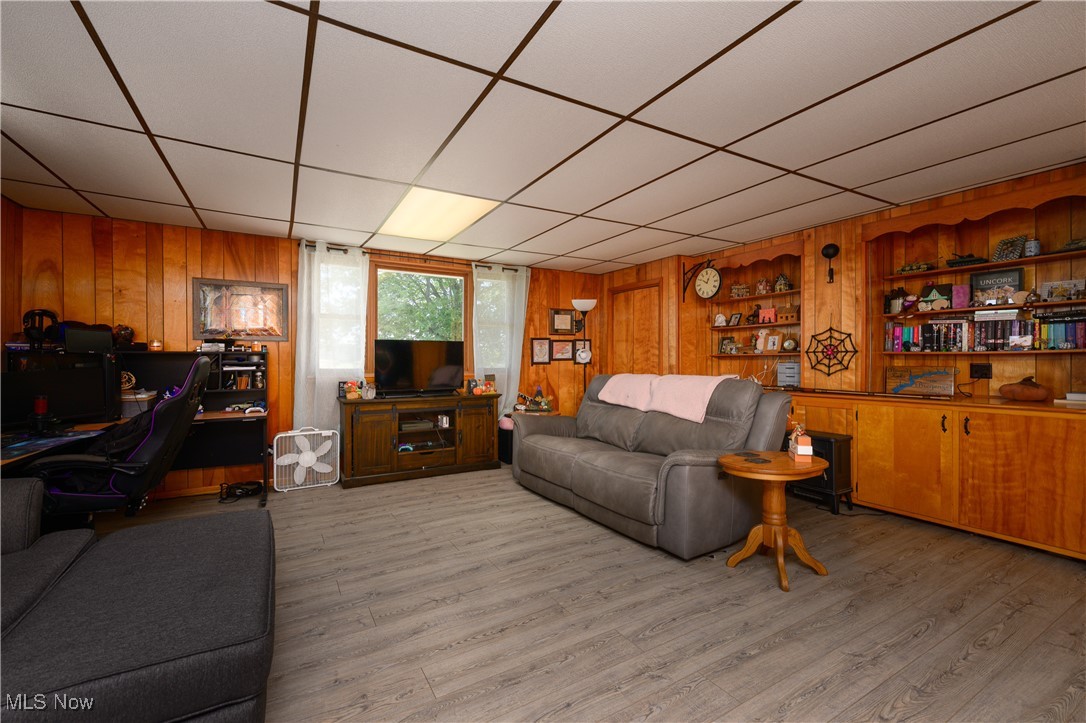 3015 Avalon Road Northwest Carrollton, OH 44615 - Photo 23 of 35 Living room featuring an office area, a paneled ceiling, wood walls, and light wood-type flooring