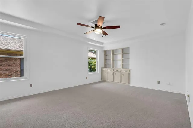 an empty room with windows and fan