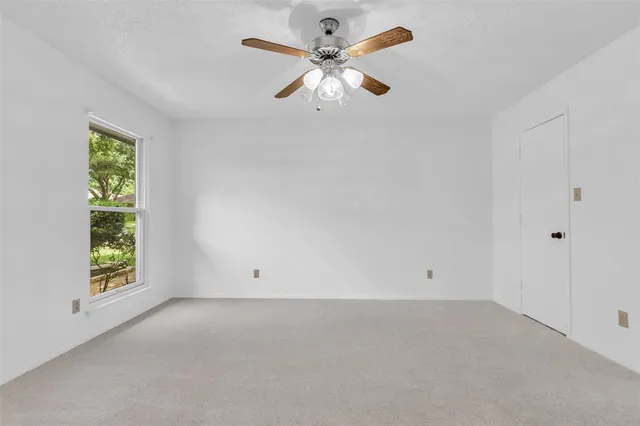 an empty room with a window and a ceiling fan