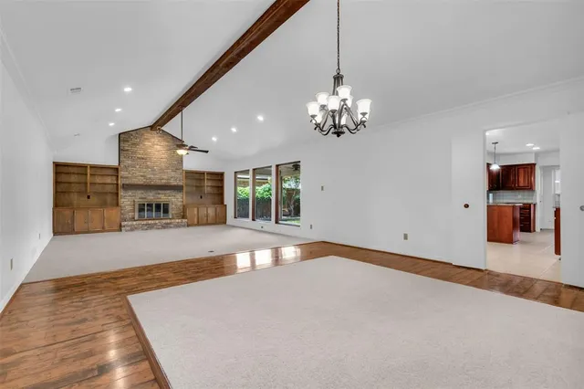a view of an empty room with a fireplace and chandelier