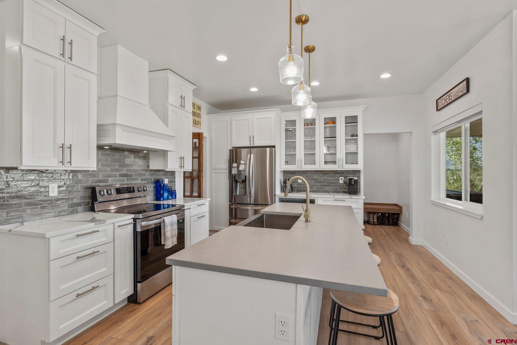 1517 Golf Course Lane Cortez, CO 81321 - Photo 9 of 41 a kitchen with kitchen island a stove a sink a refrigerator and white cabinets with wooden floor