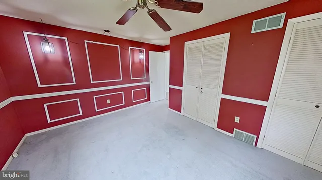 a view of an empty room with wooden floor and cabinet with a mirror
