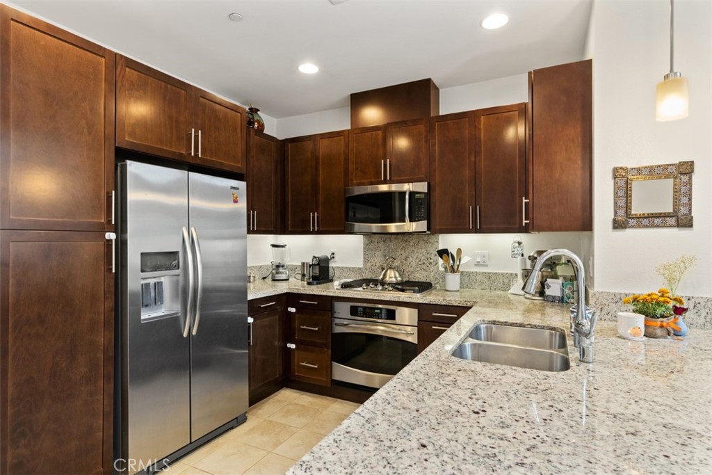 a kitchen with stainless steel appliances granite countertop a refrigerator a sink a stove a microwave and island