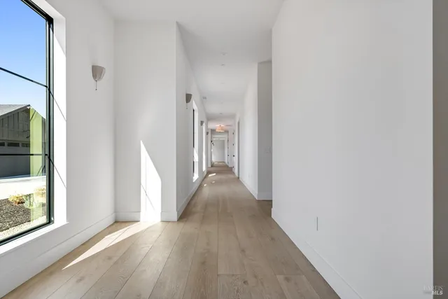 a view of a hallway with wooden floor and a living room