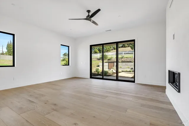 a view of an empty room with a window and a kitchen