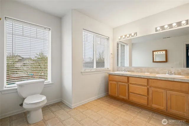 a bathroom with a granite countertop toilet a sink and a window