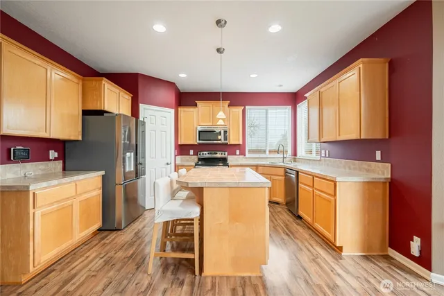 a kitchen with stainless steel appliances granite countertop a refrigerator a stove top oven a sink dishwasher and wooden cabinets with wooden floor