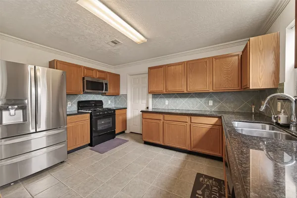 a kitchen with granite countertop a stove top oven sink and cabinets