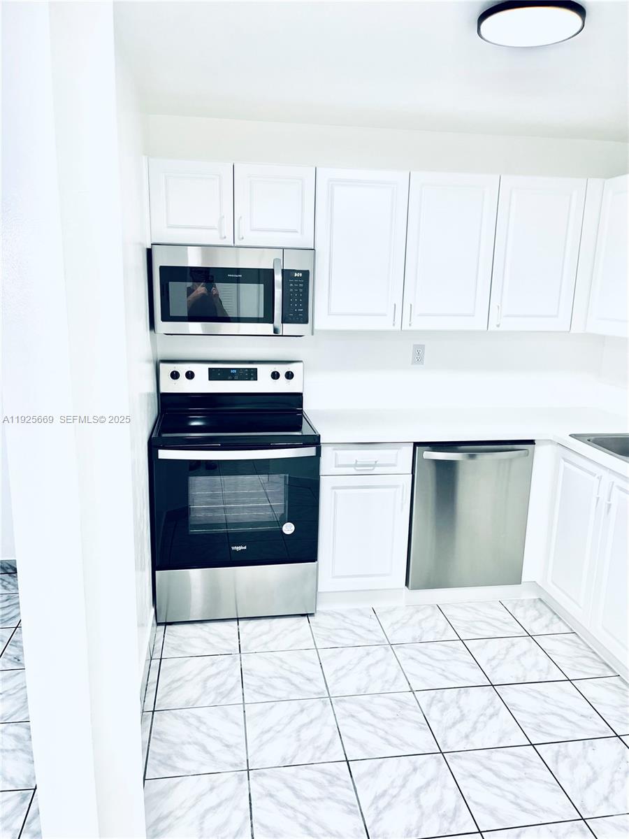 6801 Harding Avenue, Unit 306 Miami Beach, FL 33141 - Photo 15 of 30 a kitchen with stainless steel appliances a stove a sink and a microwave