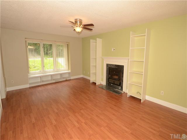 1328 Princess Anne Road Cary, NC 27513 - Photo 3 of 20 an empty room with wooden floor fireplace and windows