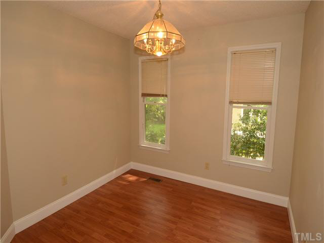 1328 Princess Anne Road Cary, NC 27513 - Photo 7 of 20 an empty room with wooden floor chandelier and windows
