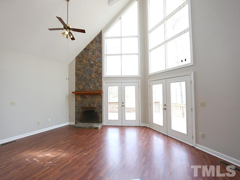 4791 Thomas Road Henderson, NC 27537 - Photo 10 of 25 an empty room with wooden floor fireplace and windows