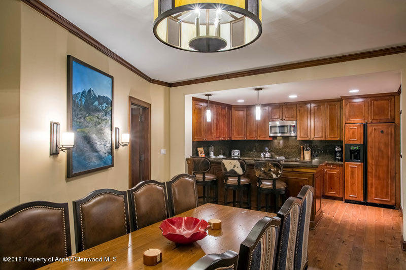 197 Prospector Road, Unit 230612 Aspen, CO 81611 - Photo 10 of 27 a kitchen with stainless steel appliances granite countertop a stove a refrigerator a sink a dining table and chairs with wooden floor