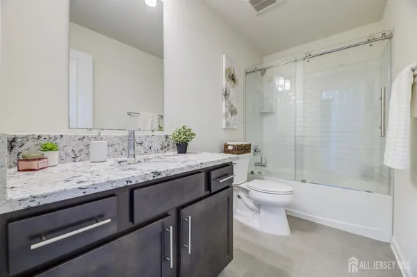 a bathroom with a granite countertop sink a toilet and shower