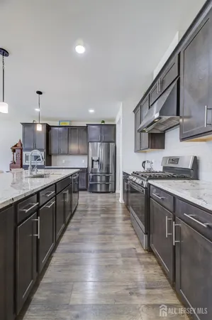 a large kitchen with stainless steel appliances granite countertop a lot of counter space and wooden floors