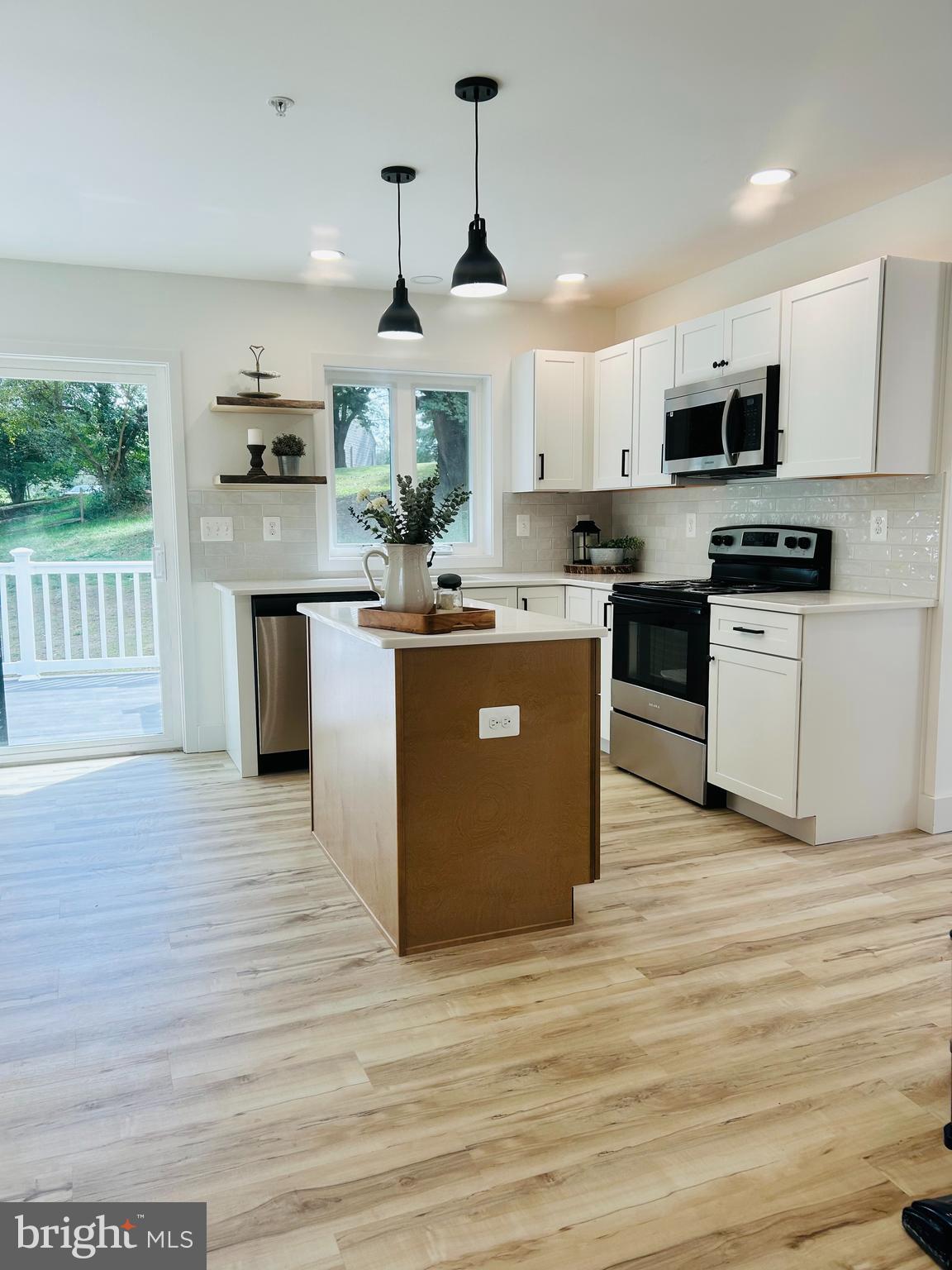296 Post Road Rising Sun, MD 21911 - Photo 3 of 12 a kitchen with stainless steel appliances granite countertop a stove top oven a sink dishwasher a refrigerator and a dining table with wooden floor