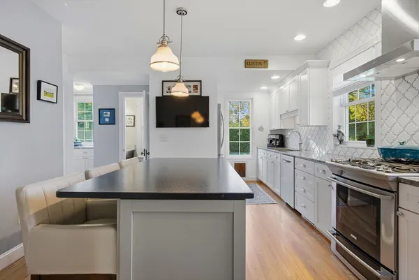 a kitchen with stainless steel appliances granite countertop a stove a sink a microwave a refrigerator white cabinets and couches