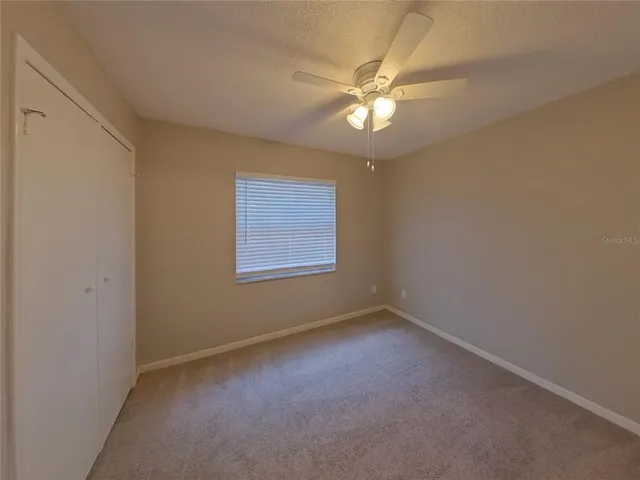 an empty room with a chandelier fan and windows