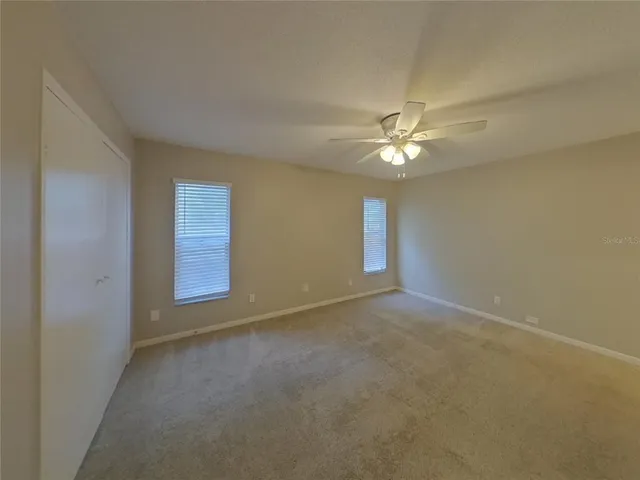an empty room with windows and fan