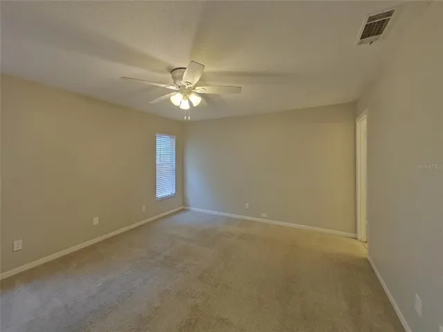 an empty room with a chandelier fan and windows