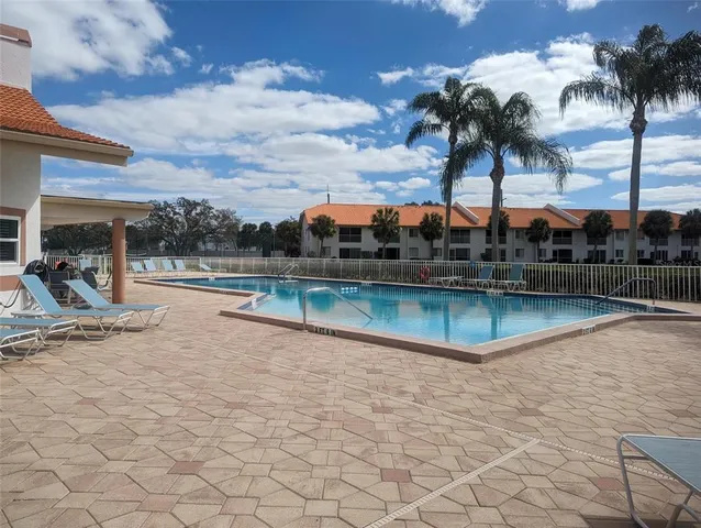 a view of a swimming pool with a lawn chairs under an umbrella