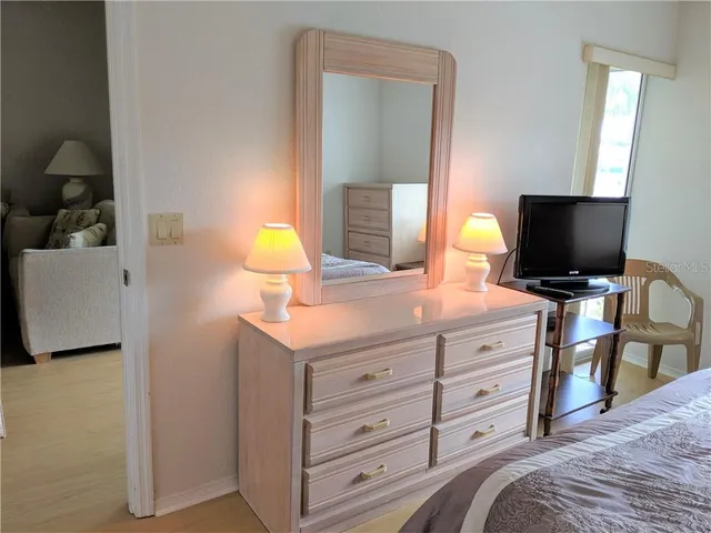 a bedroom with a bed and a flat tv screen on dresser