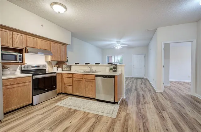 a kitchen with a refrigerator a sink and dishwasher with wooden floor