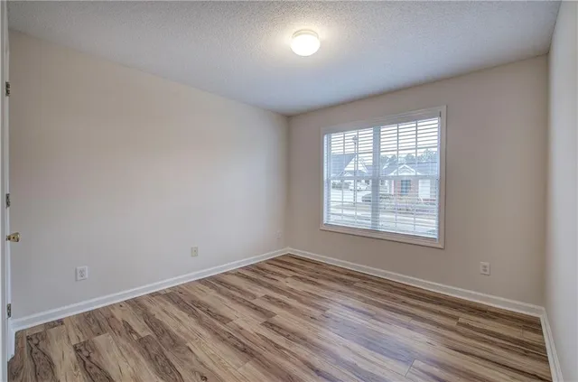 a view of an empty room with wooden floor and closet